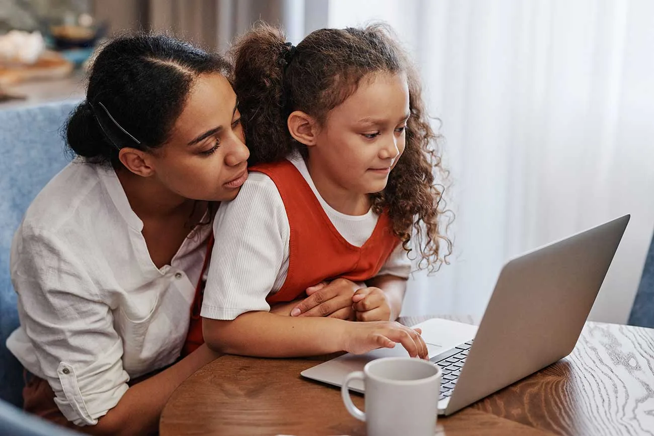 Mother and child review a family technology agreement on a laptop